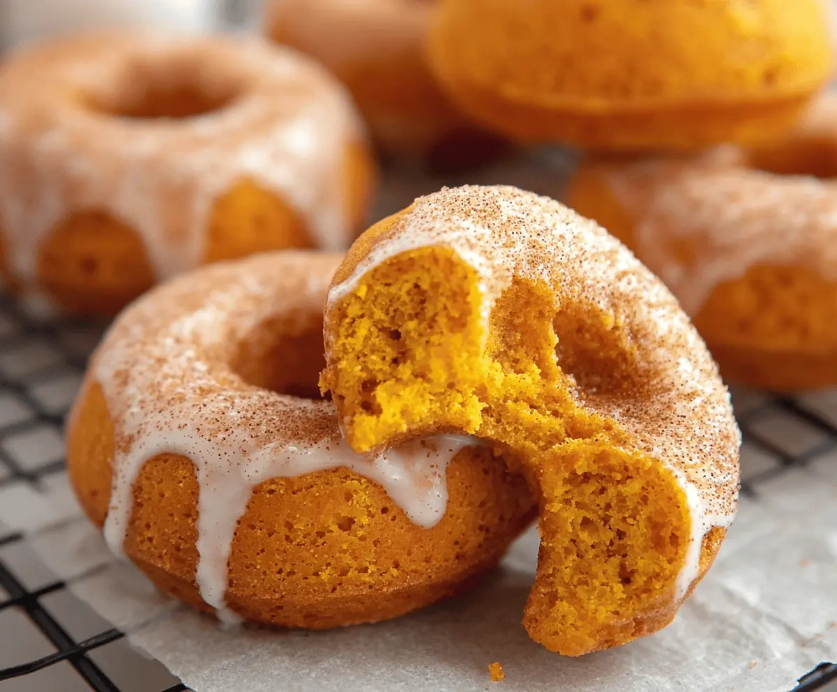 Delicious baked pumpkin cake donuts topped with a sprinkle of cinnamon and powdered sugar on a rustic wooden surface