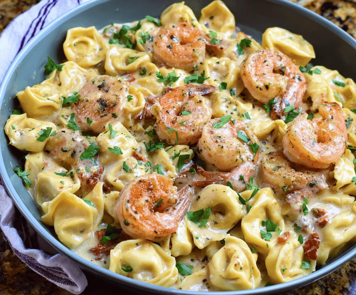 Creamy shrimp and cheese tortellini Alfredo dish garnished with fresh herbs on a white plate