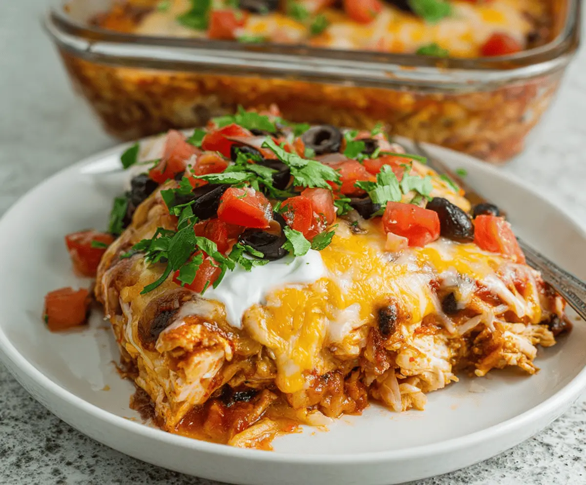 Delicious chicken burrito casserole topped with melted cheese, fresh cilantro, and diced tomatoes, served in a baking dish