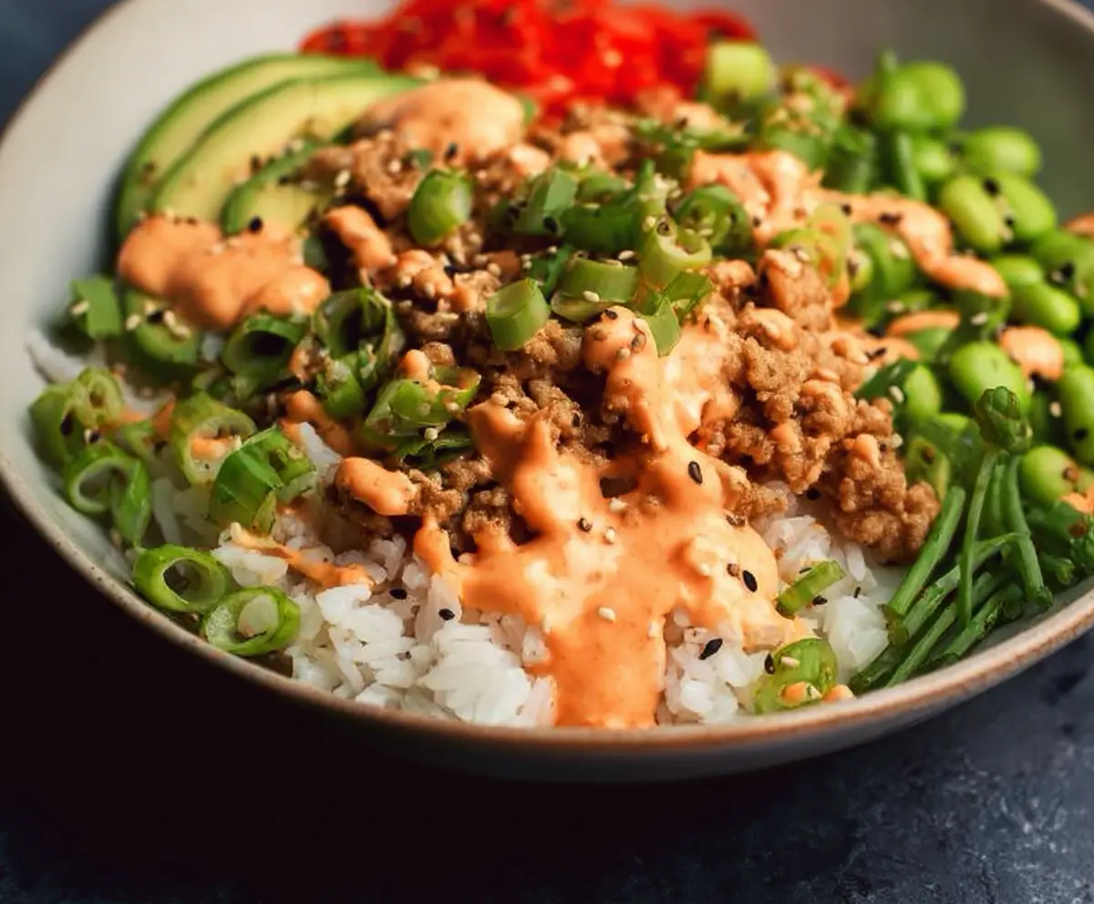 Ground turkey rice bowls topped with vibrant Bang Bang sauce, garnished with green onions and sesame seeds.