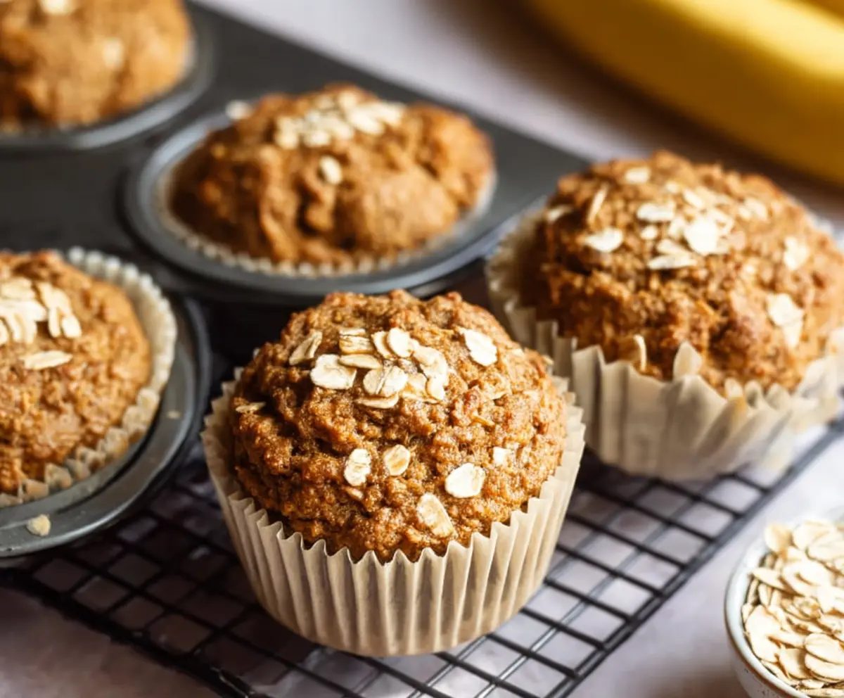 Freshly baked healthy banana oatmeal muffins on a plate, showcasing their golden crust and moist interior.